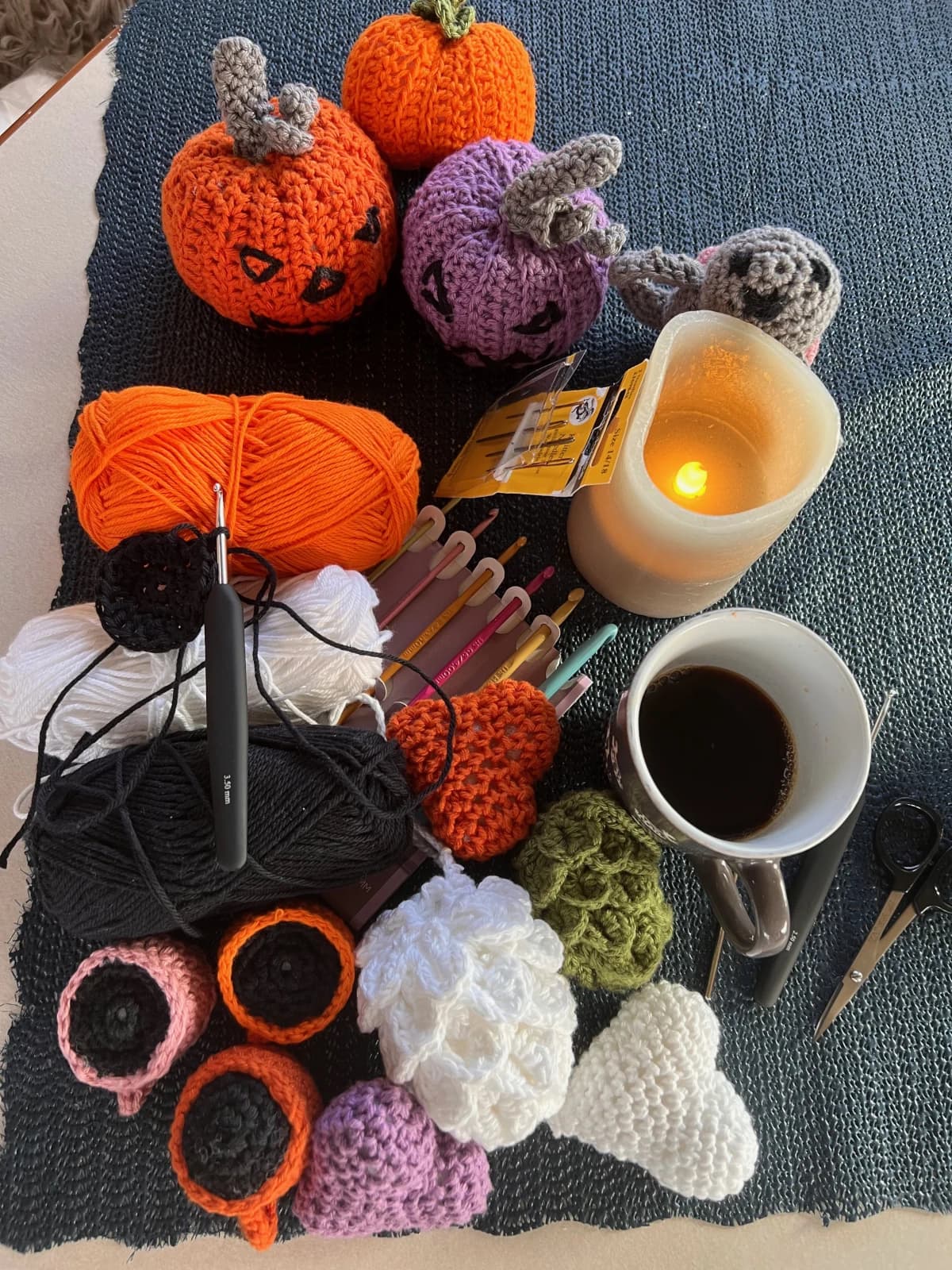Heklede figurer, fargerikt garn og heklenåler sammen med en kopp kaffe